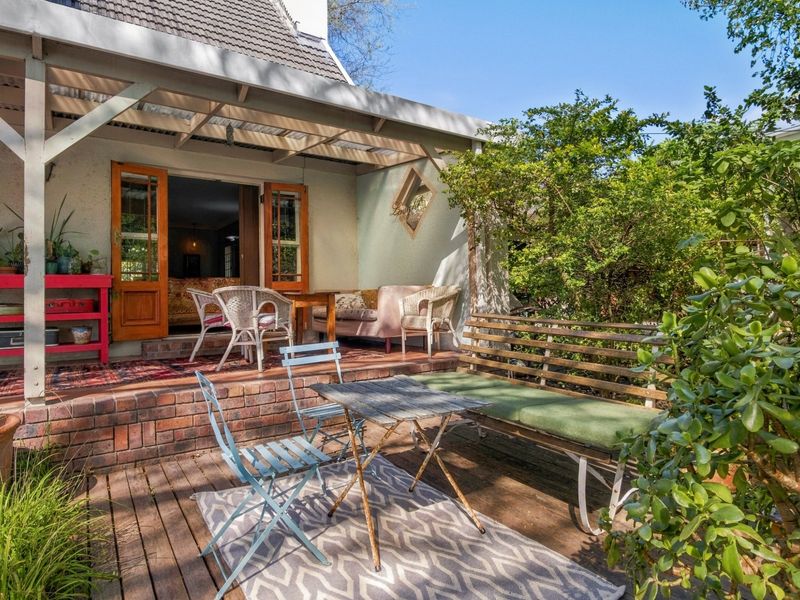A covered outdoor patio area featuring brick steps, timber decking, and direct access to the interior through timber-framed glass doors.