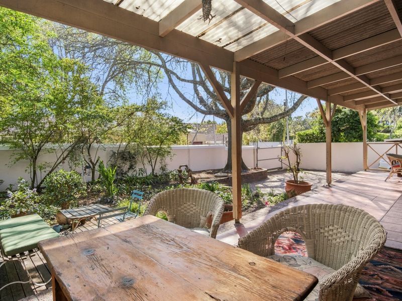Covered outdoor patio featuring a timber pergola with translucent roofing, tiled flooring, and direct access to a private garden area.