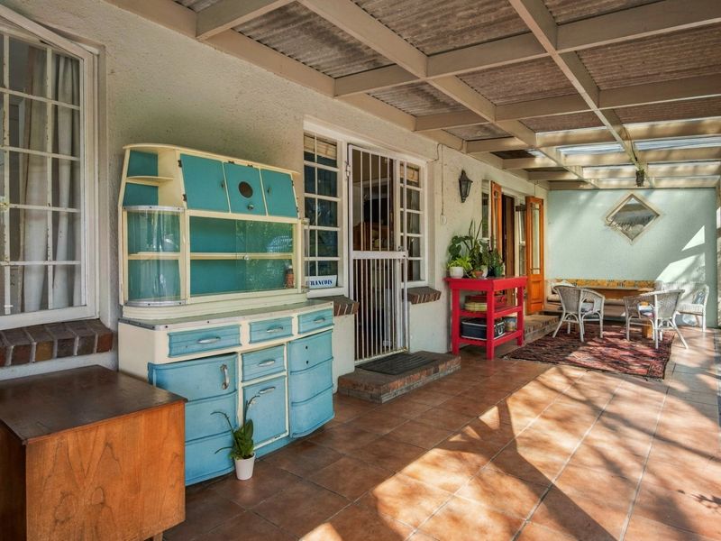 A covered outdoor patio area featuring tiled flooring and a corrugated roof, providing a functional space for outdoor living.
