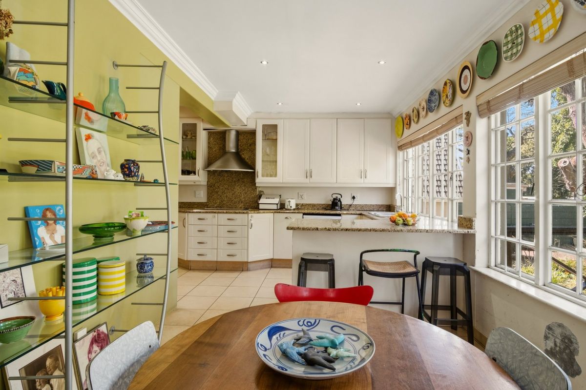A bright kitchen featuring granite countertops, ample built-in cabinetry, a breakfast bar, and tiled flooring, illuminated by recessed lighting.