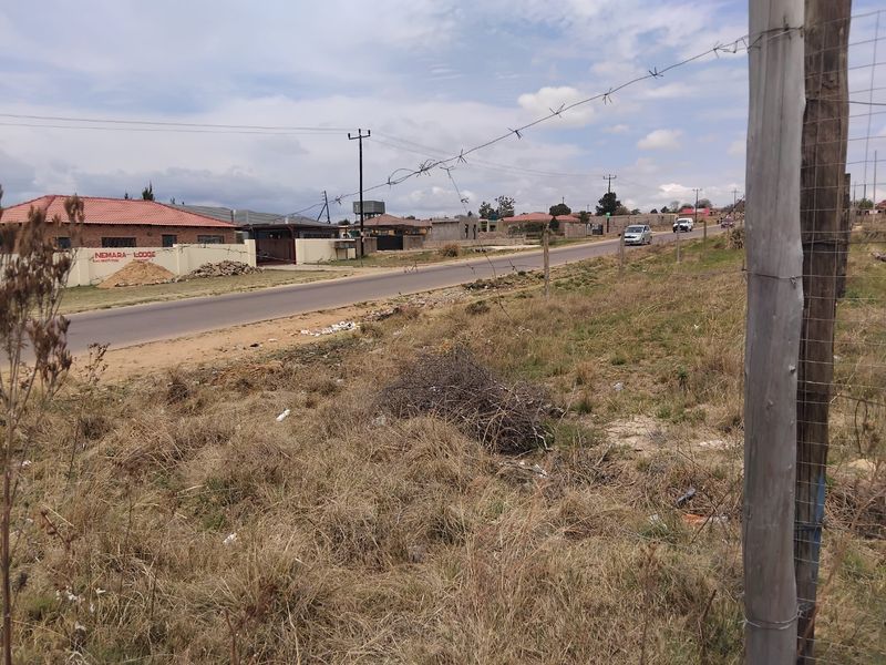 A street-level view of the vacant residential land, showing the roadside boundary, fencing, and surrounding neighborhood context.