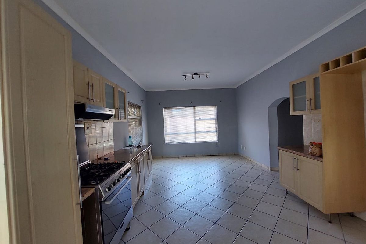 Spacious kitchen featuring built-in cabinetry, gas stove with extractor fan, tiled flooring, and a neutral color palette, offering a functional layout.