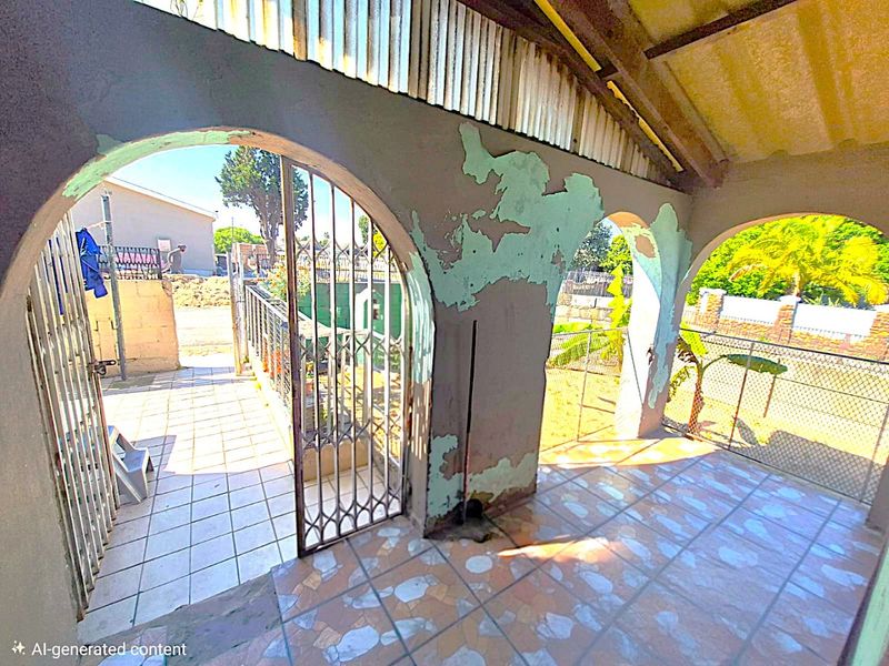 A covered patio area featuring arched openings, tiled flooring, and a metal security gate, currently showing significant wear to the wall finishes.