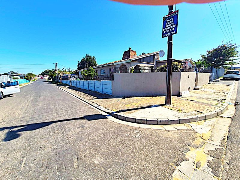 Street view of the property corner showing the boundary wall, paved sidewalk, and exterior building facade.