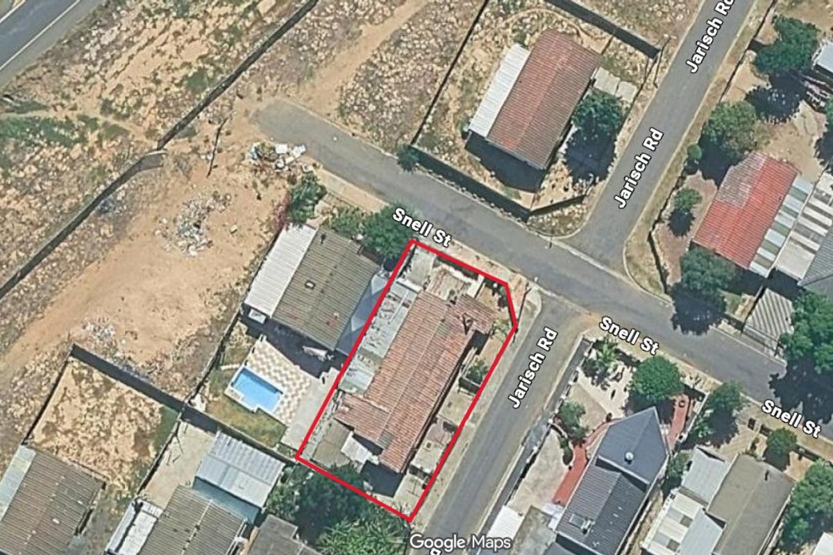 Aerial view of the property corner lot, highlighting the building footprint, roof structure, and surrounding street layout.
