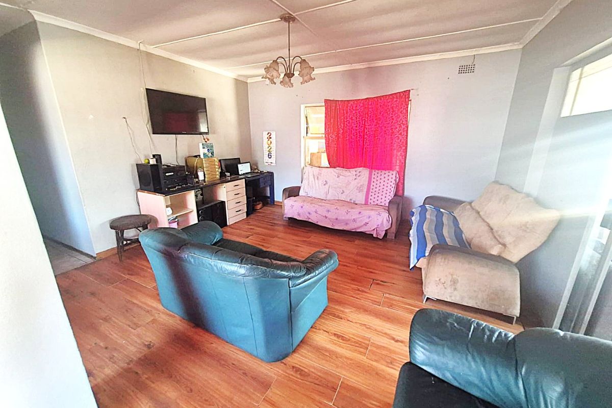 A living room featuring laminate flooring and a central pendant light fixture, offering a functional space ready for cosmetic updates and modernization.