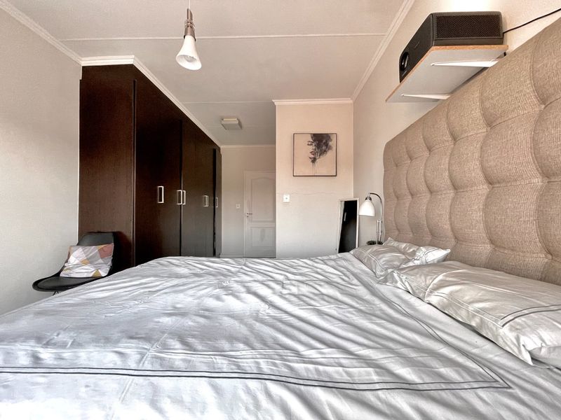 A well-maintained bedroom featuring extensive built-in dark wood cabinetry, neutral walls, and a ceiling-mounted projector setup.