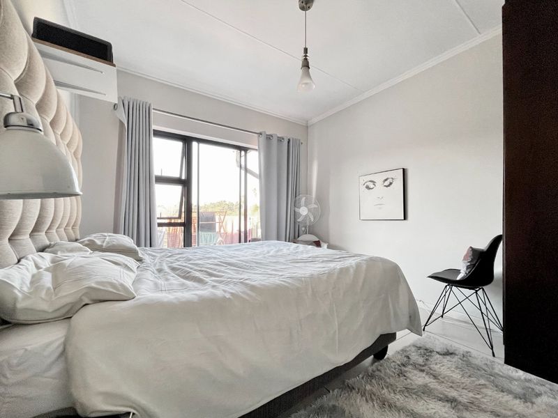A well-lit bedroom featuring neutral walls, a coved ceiling, and an aluminium sliding door providing access to the exterior.