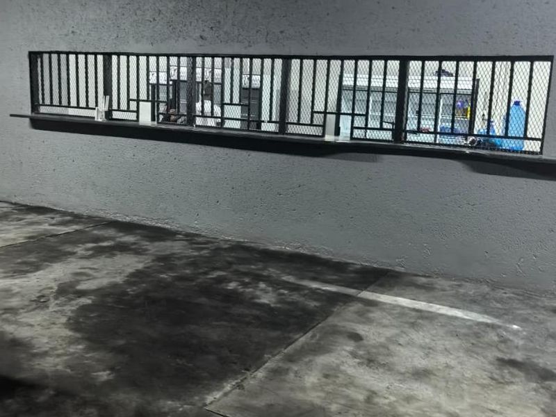 A utilitarian commercial space featuring a service counter with a security grille and stained concrete flooring.