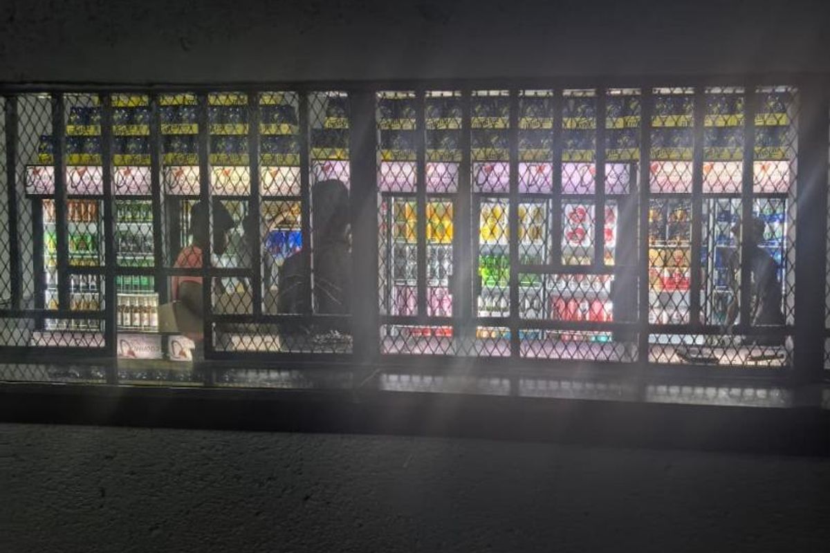 A dimly lit interior view featuring a service counter protected by a heavy-duty metal security grille.