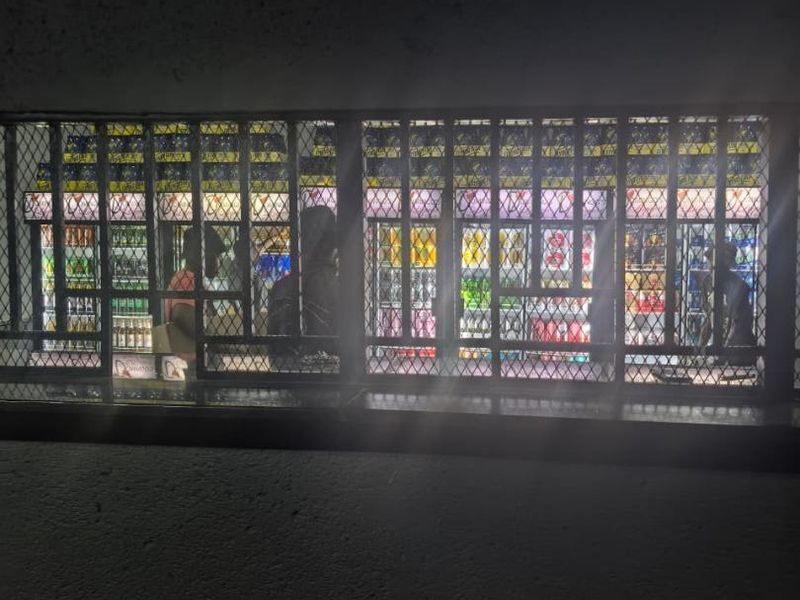 A dimly lit interior view featuring a service counter protected by a heavy-duty metal security grille.
