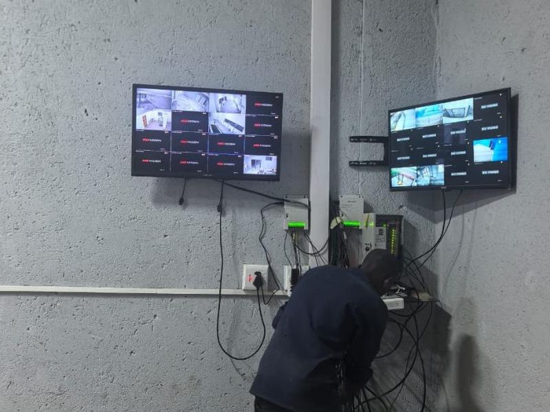 Utility space featuring wall-mounted CCTV surveillance monitors and exposed network infrastructure cabling.