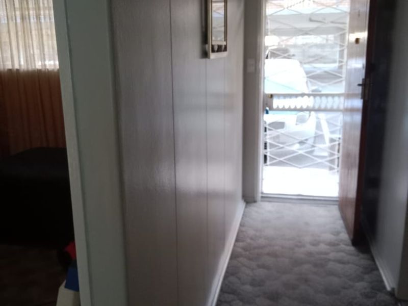 An entry hallway featuring carpeted flooring and a security gate at the front door, providing access to the main living area.
