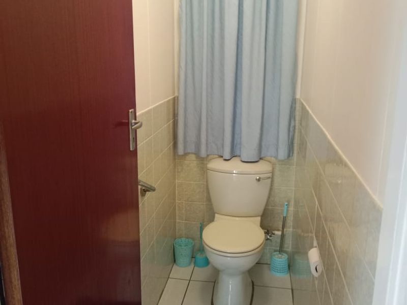 A compact bathroom featuring a standard toilet, tiled flooring, and wall tiling, providing a functional and clean space.