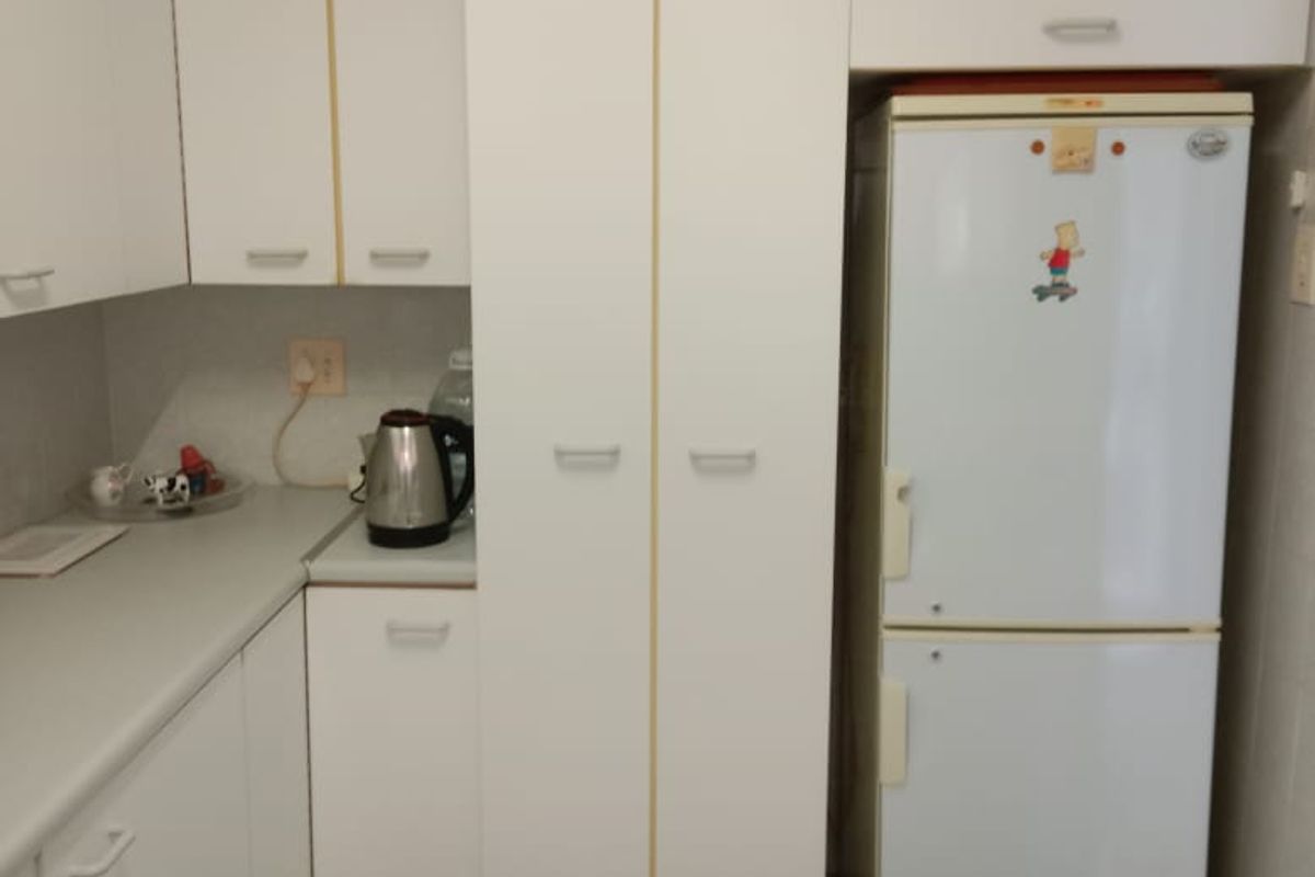 A functional kitchen featuring white built-in cabinetry, laminate countertops, and tiled flooring, providing a clean and practical workspace.