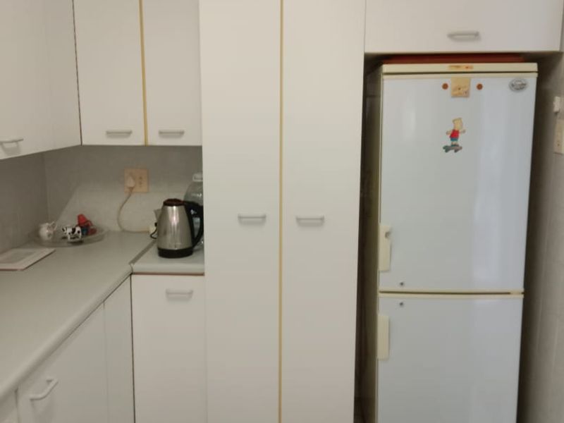 A functional kitchen featuring white built-in cabinetry, laminate countertops, and tiled flooring, providing a clean and practical workspace.