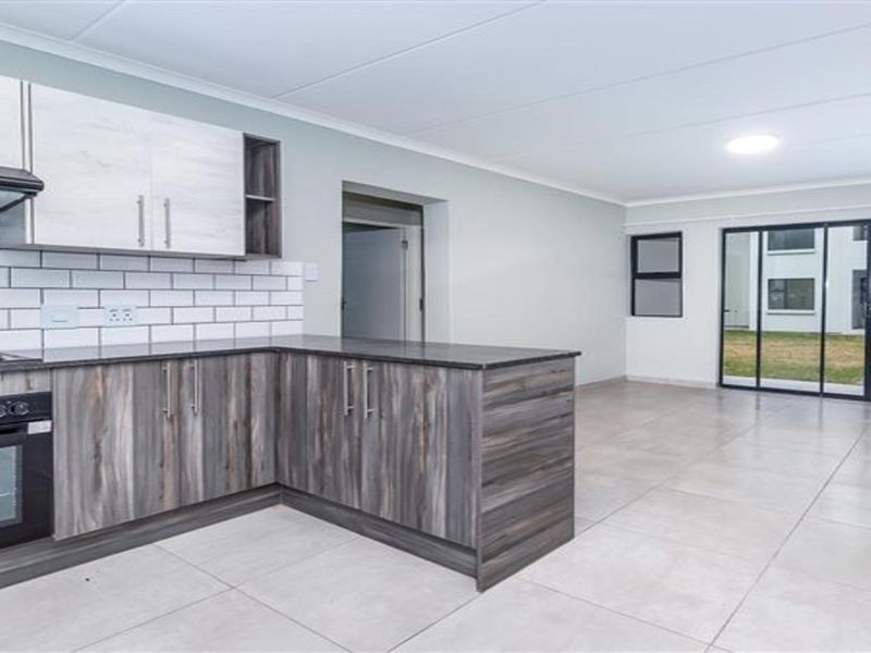 Modern open-plan kitchen and living area featuring contemporary cabinetry, subway tile backsplash, and large sliding glass doors leading to an outdoor space.