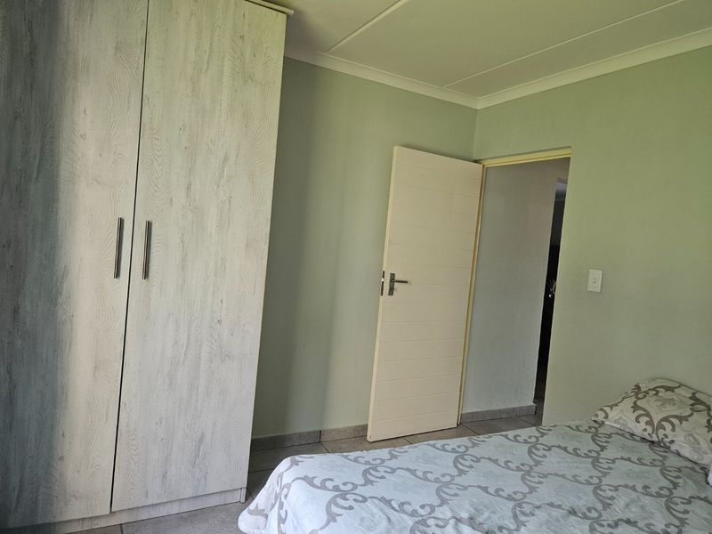 A bedroom featuring built-in wardrobes, tiled flooring, and neutral wall finishes, providing a functional and clean living space.
