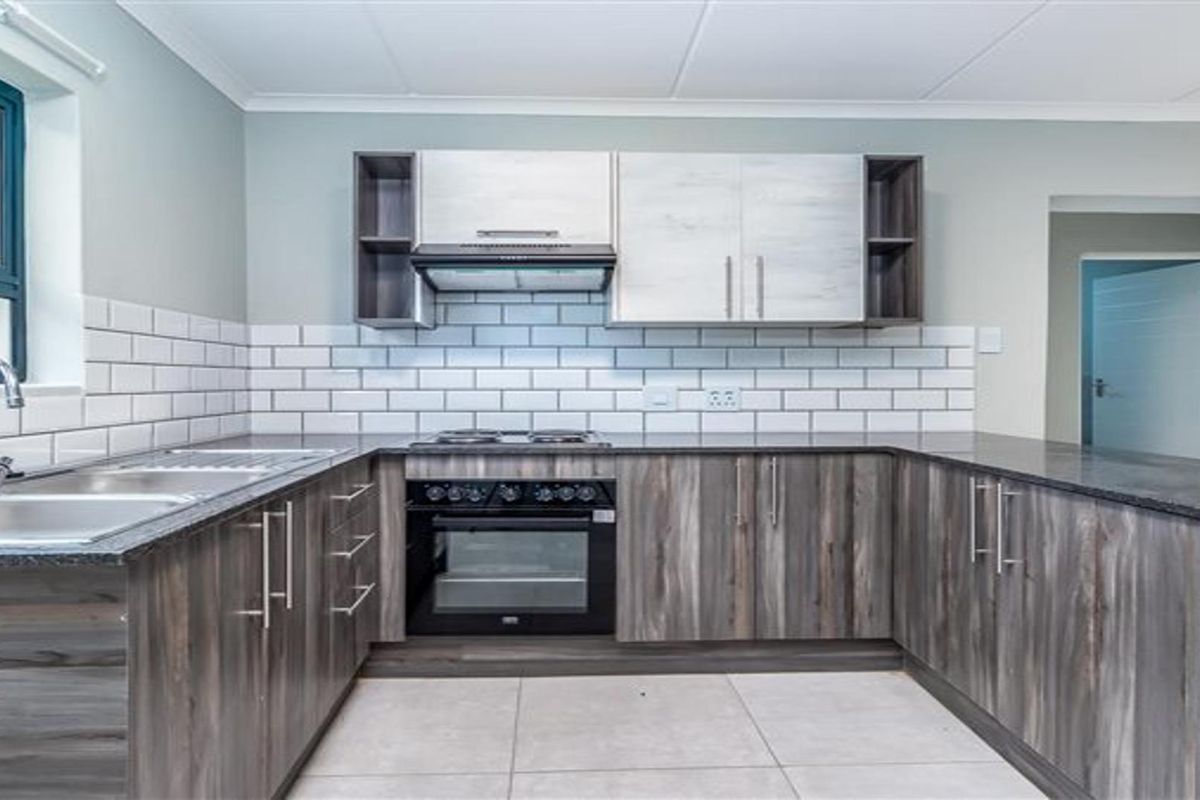 A modern, well-maintained kitchen featuring dark wood-grain cabinetry, granite countertops, a subway tile backsplash, and integrated stainless steel appliances.