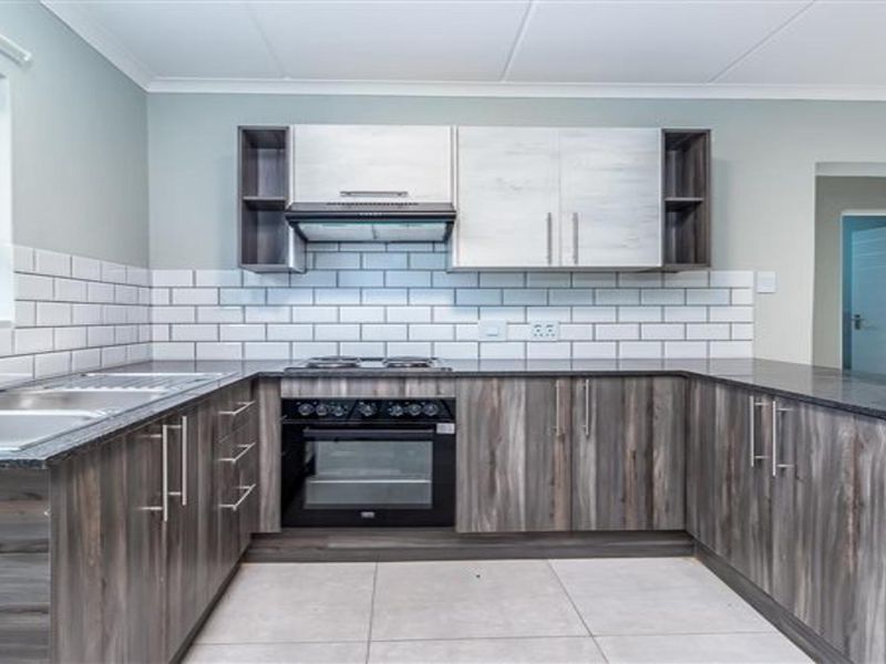 A modern, well-maintained kitchen featuring dark wood-grain cabinetry, granite countertops, a subway tile backsplash, and integrated stainless steel appliances.