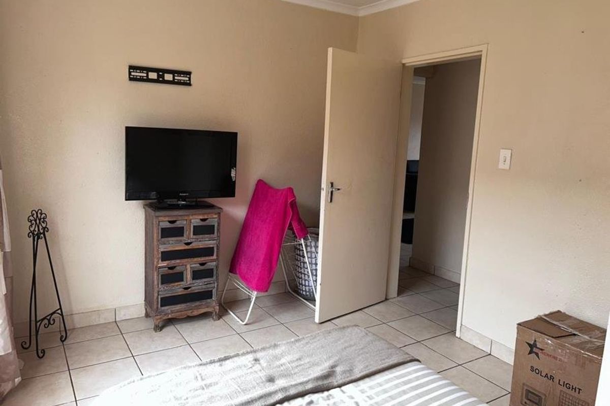 A bedroom featuring tiled flooring and neutral wall finishes, providing a functional space with direct access to an adjoining room.