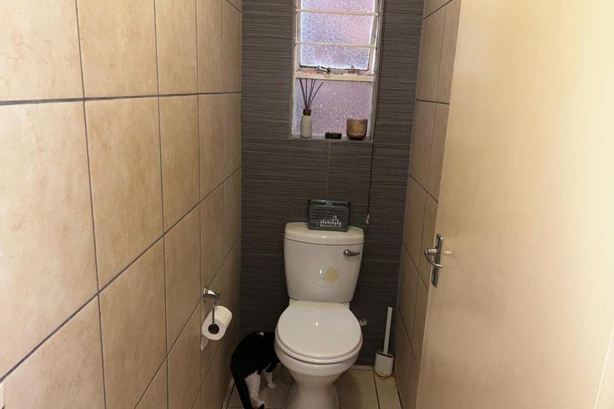 A compact guest bathroom featuring tiled walls, tiled flooring, and a window with security bars.