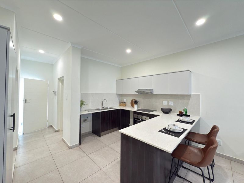 Modern kitchen featuring dark wood cabinetry, light stone countertops, integrated appliances, and a breakfast bar, finished with neutral floor tiles and recessed lighting.