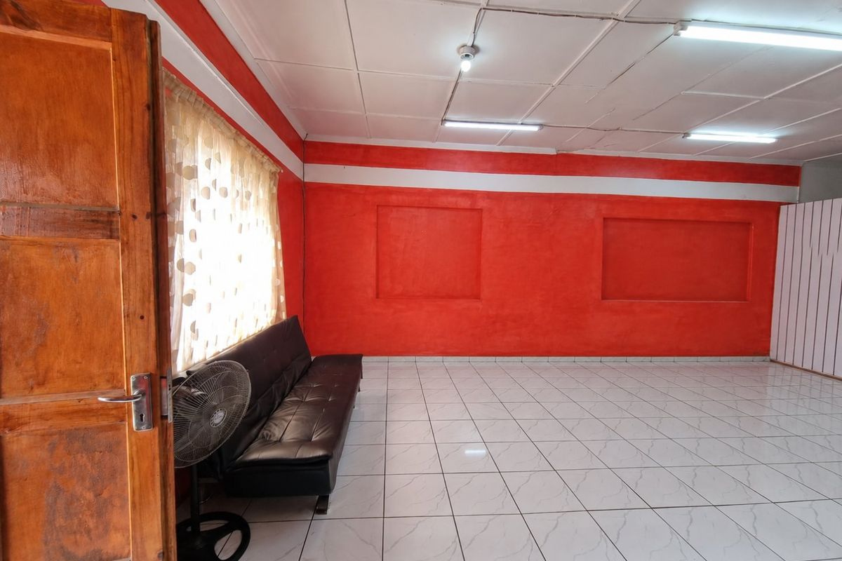 A living room featuring tiled flooring, recessed wall niches, and fluorescent lighting, currently finished with bold red wall paint.