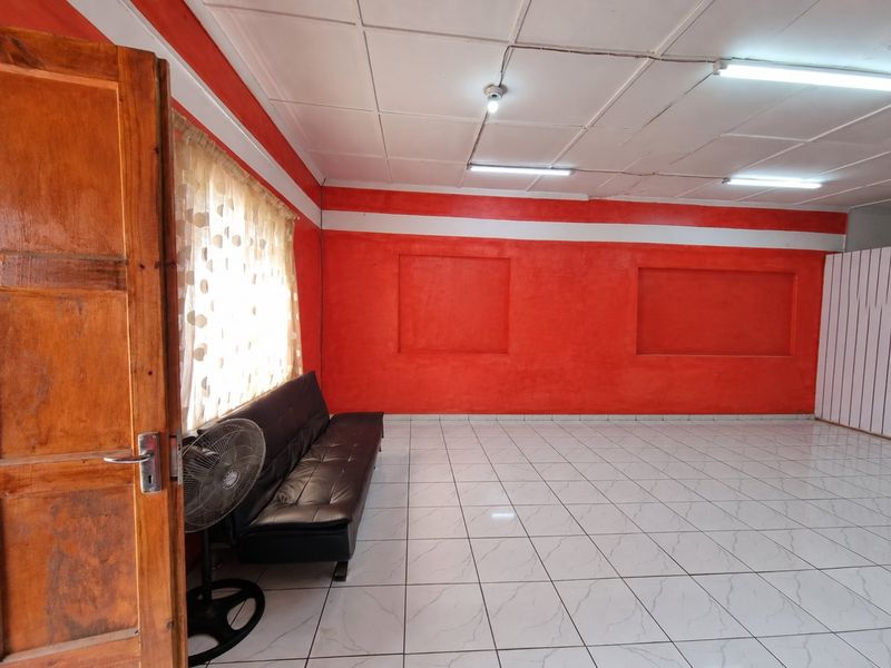 A living room featuring tiled flooring, recessed wall niches, and fluorescent lighting, currently finished with bold red wall paint.