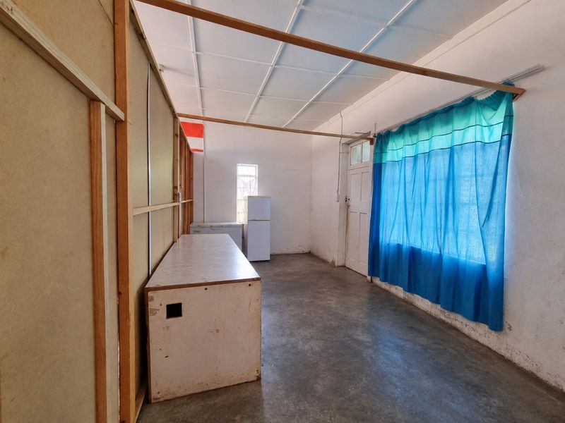 A basic utility or storage space featuring concrete flooring, a tiled ceiling, and a temporary timber partition structure.