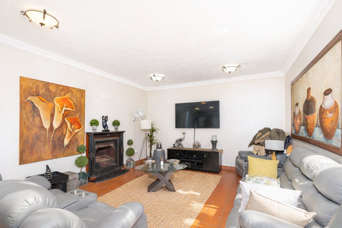 A comfortable living room featuring a built-in fireplace, terracotta floor tiles, and classic ceiling cornicing, providing a warm and inviting space.