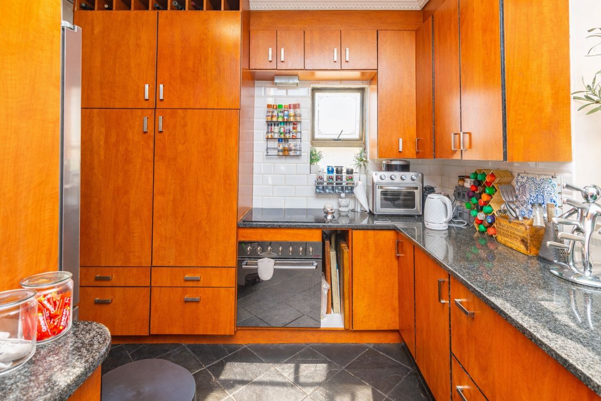 A functional kitchen featuring warm-toned wooden cabinetry, granite countertops, a subway tile backsplash, and integrated cooking appliances.