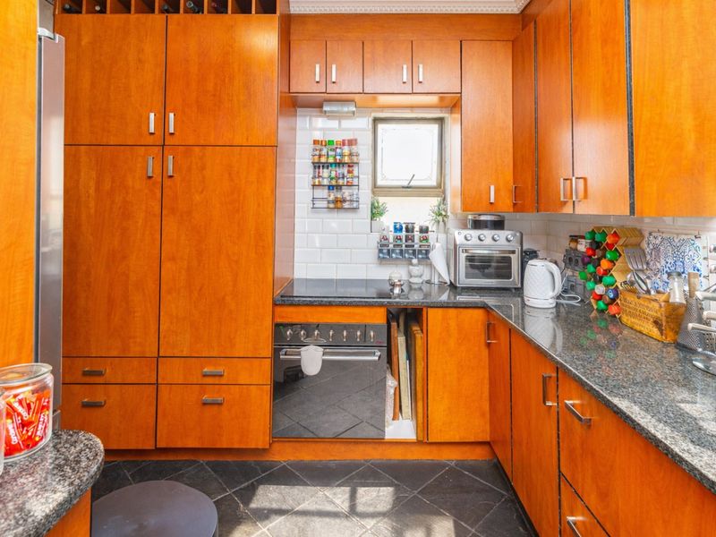 A functional kitchen featuring warm-toned wooden cabinetry, granite countertops, a subway tile backsplash, and integrated cooking appliances.