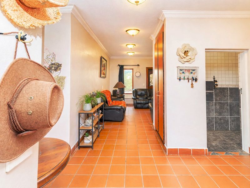 A tiled hallway featuring coving and built-in storage, leading towards a living area and a tiled bathroom space.