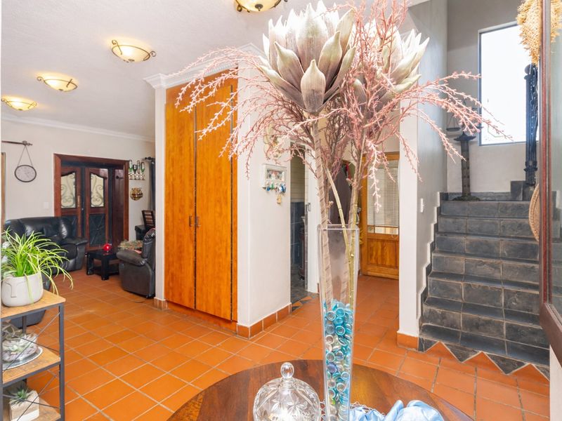 An inviting entrance hall featuring terracotta tiled flooring, built-in wooden storage cabinetry, and a staircase leading to the upper level.