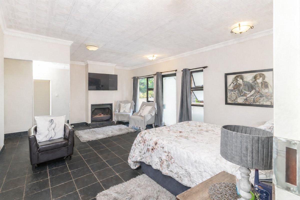 Spacious bedroom featuring dark tiled flooring, a built-in fireplace, textured ceiling tiles, and direct access to the exterior through a glass door.