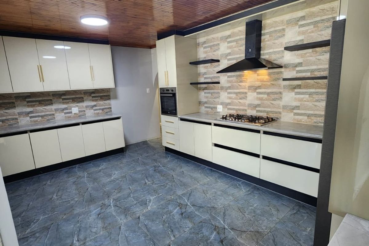 Modern kitchen featuring high-gloss cabinetry, stone-look backsplash, gas hob with extractor, and distinctive timber-clad ceiling with marble-effect tiled flooring.