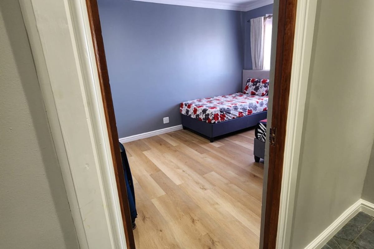 A well-maintained bedroom featuring modern laminate flooring, recessed downlighting, and decorative coving, viewed from the adjacent hallway.