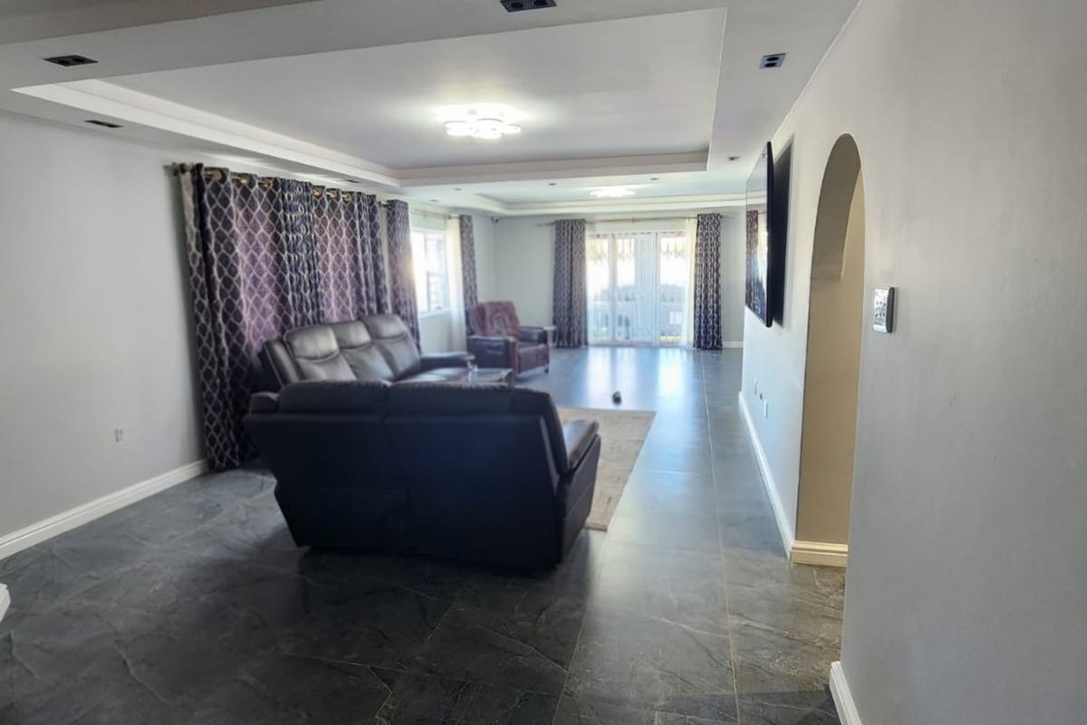 Spacious living room featuring a tray ceiling with recessed lighting, dark tiled flooring, and an elegant archway leading to adjacent areas.