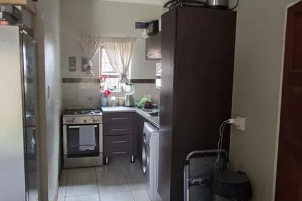 A functional kitchen featuring tiled flooring, built-in cabinetry, and a freestanding stove, offering a practical layout for daily meal preparation.