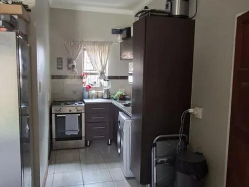 A functional kitchen featuring tiled flooring, built-in cabinetry, and a freestanding stove, offering a practical layout for daily meal preparation.