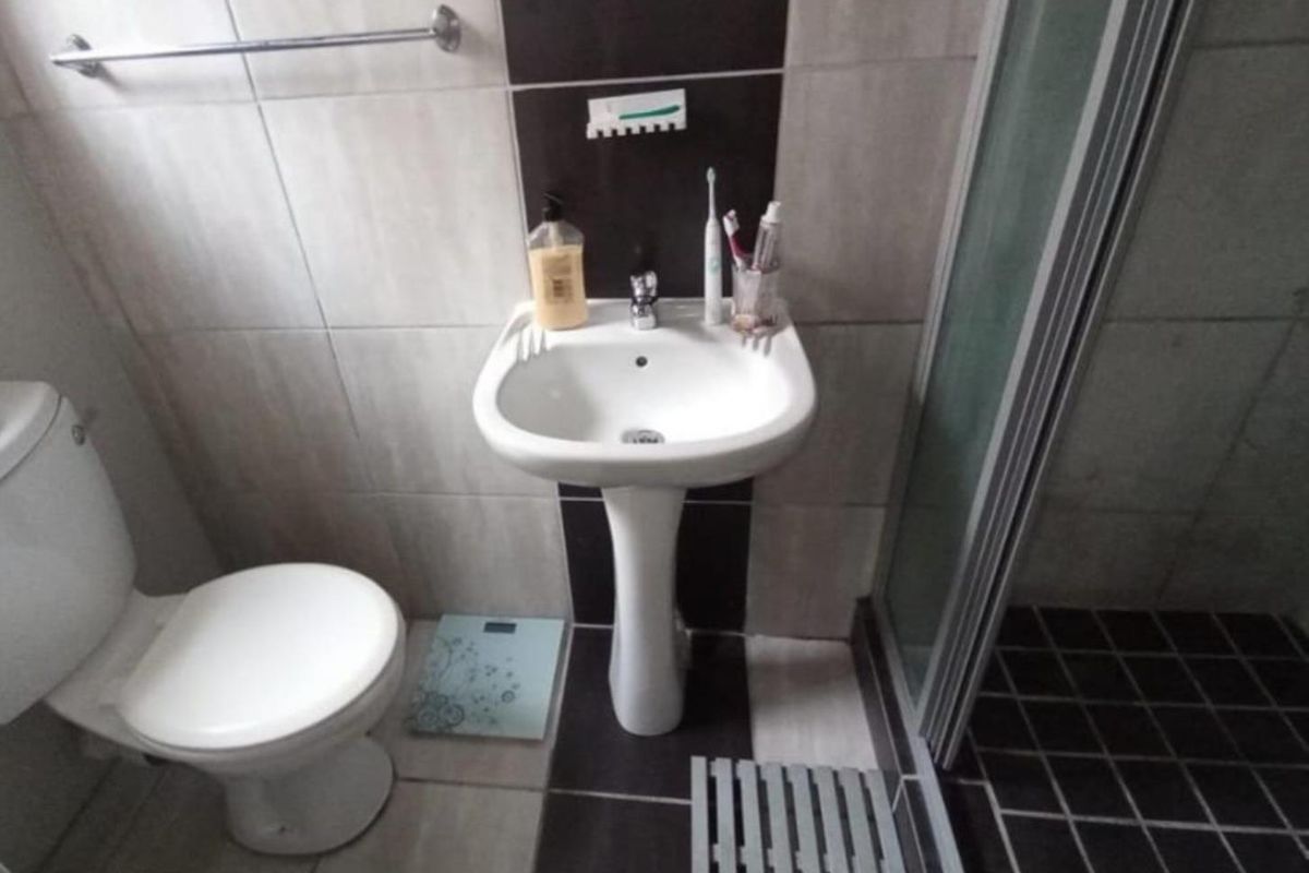 A compact bathroom featuring a pedestal basin, toilet, and a shower enclosure with tiled finishes throughout.