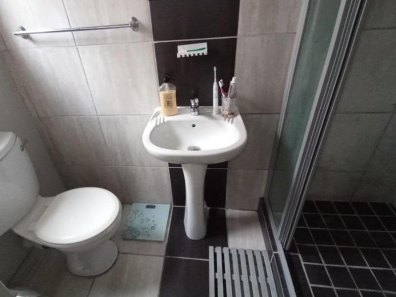 A compact bathroom featuring a pedestal basin, toilet, and a shower enclosure with tiled finishes throughout.