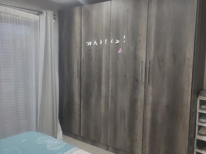 A bedroom featuring large, wood-finish built-in cupboards, tiled flooring, and modern recessed lighting.