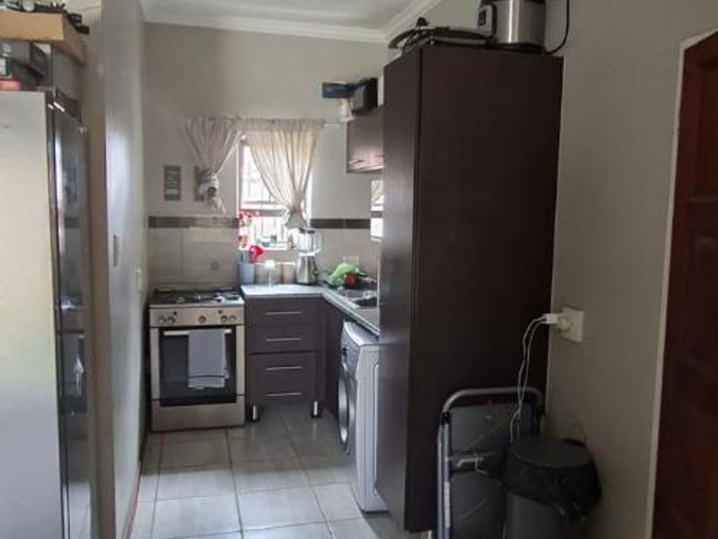 A functional galley-style kitchen featuring tiled flooring, built-in cabinetry, a tiled backsplash, and a freestanding stove.