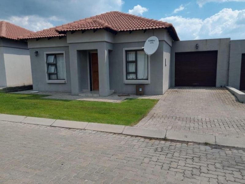 Front elevation of a modern townhouse featuring a tiled roof, paved driveway, integrated garage, and aluminium window frames.