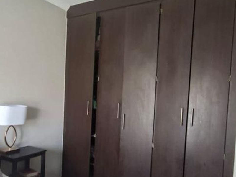 A bedroom featuring dark wood built-in cupboards and tiled flooring.