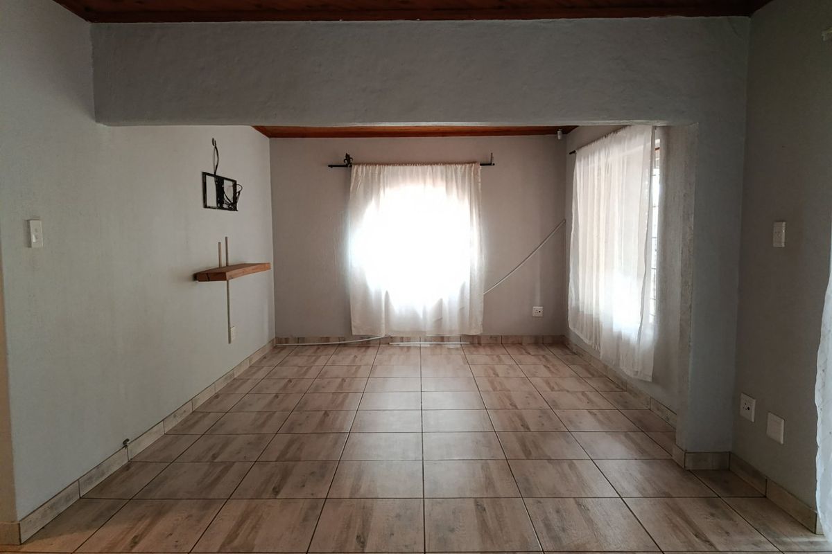 An empty living room featuring tiled flooring and a timber ceiling, offering a blank canvas for potential interior design and renovation.