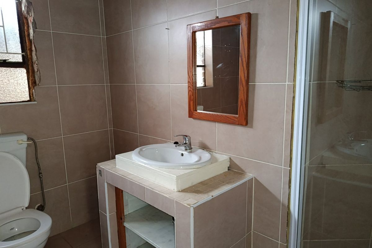 A bathroom featuring tiled walls and flooring, a built-in vanity with a ceramic basin, a toilet, and a shower enclosure.