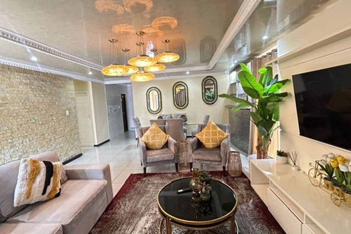 Spacious living room featuring a textured stone accent wall, glossy ceiling with decorative molding, and polished floor tiles.